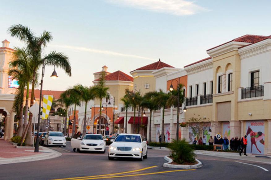 Street view of Gulfstream Park Towers with cars and palm trees lining the road.