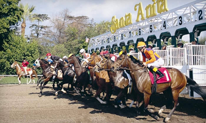 Horses and jockeys exiting the starting gate at Santa Anita Park during a race.