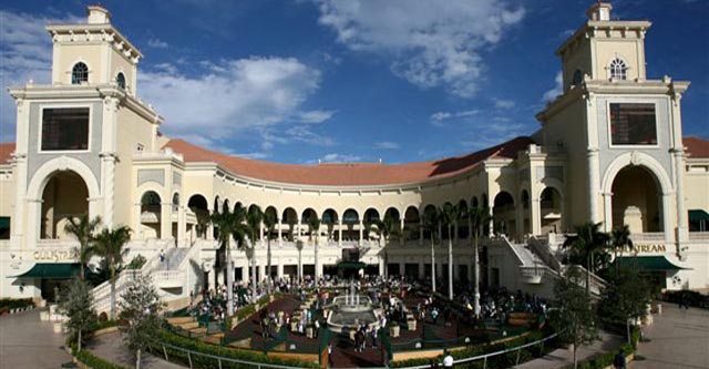 Exterior view of Gulfstream Park, featuring a large building with arches and palm trees.