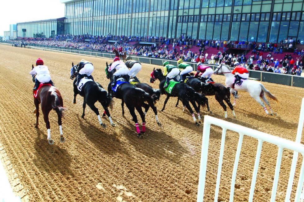 A group of racehorses competing on a dirt track during a horse race event.