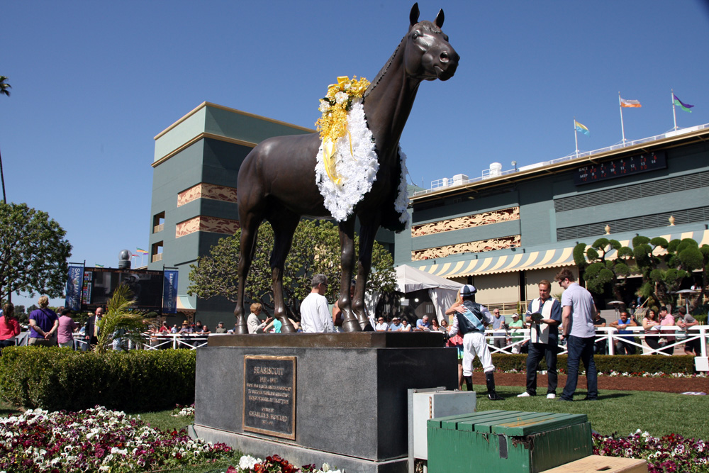 Bronze statue of a horse adorned with a floral garland, showcasing equestrian art and culture.