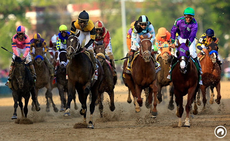 A group of horses and jockeys competing in a horse race on a dirt track.