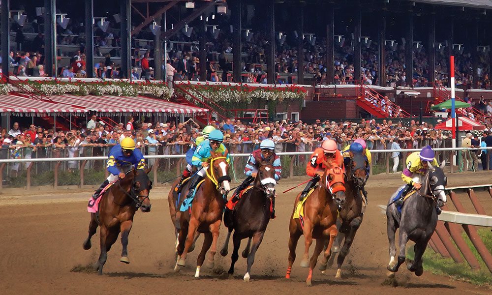 Group of horses racing at Saratoga Race Course with jockeys in colorful uniforms.