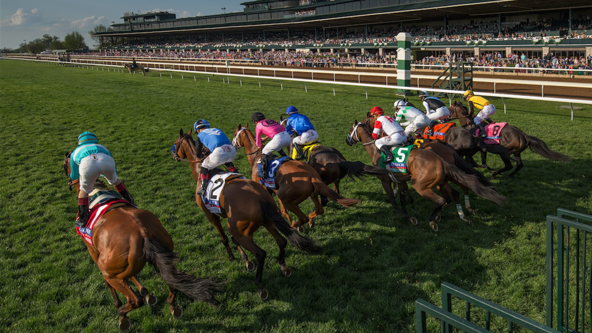 Horses racing at Keeneland during the spring meet with jockeys in colorful silks.