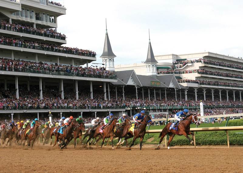Thoroughbred horses racing at a derby event with spectators in the background, showcasing the excitement of horse racing.