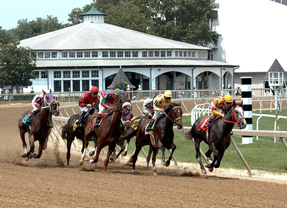 Horses racing at Laurel Park with jockeys in colorful silks on a dirt track.