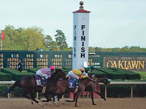 Horses racing towards the finish line at Oaklawn Park with a large finish sign in view.