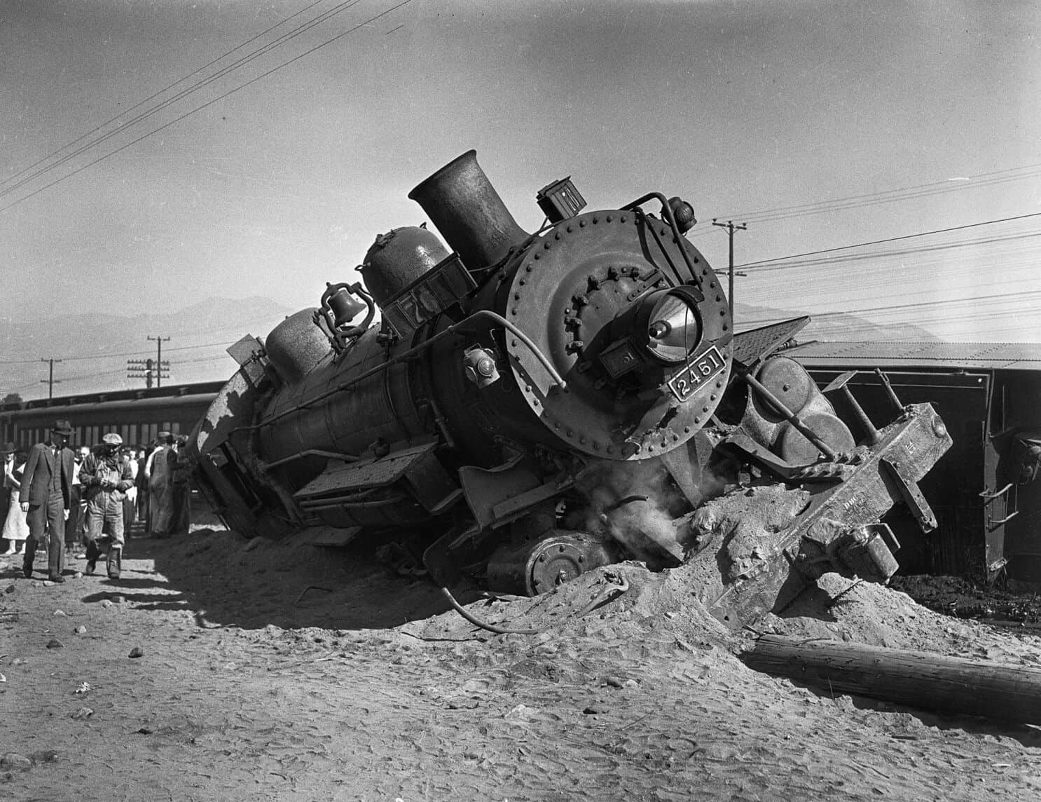 A derailed steam locomotive resting on its side, showcasing the mechanical details and structure of the train.